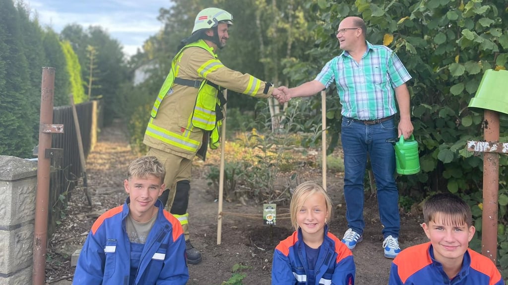 Die Baumpflanzchallenge 2025 ist geschafft: Hessens Wehrleiter André Bindseil-Almes (links) und Ortsbürgermeister Hans-Werner Goy reichen sich über dem neuen Apfelbaum die Hände. Mit ihnen freut sich der Feuerwehrnachwuchs: Max Nehrig, Stella Almes und Lukas Schulz (von links).