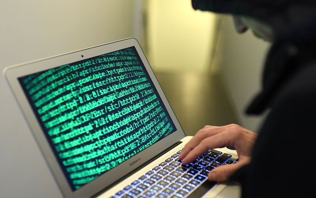 Das Symbolbild soll einen Cyberkriminellen an einem Laptop darstellen.