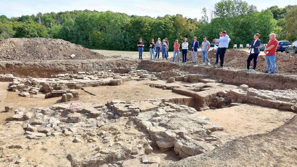 Professor Felix Biermann (3.v.r.) präsentiert Grabungsergebnisse am Kloster Kaltenborn. Zu den Funden gehören ein Schmuckbeschlag für eine Messerscheide in Form eines Hundes, ein Gewicht mit Kreuz-Dekor, ein Stuck-Fragment, Münzen (oben v.l.n.r.) und kleine Tonschälchen aus einem Keller (Mi. l.).