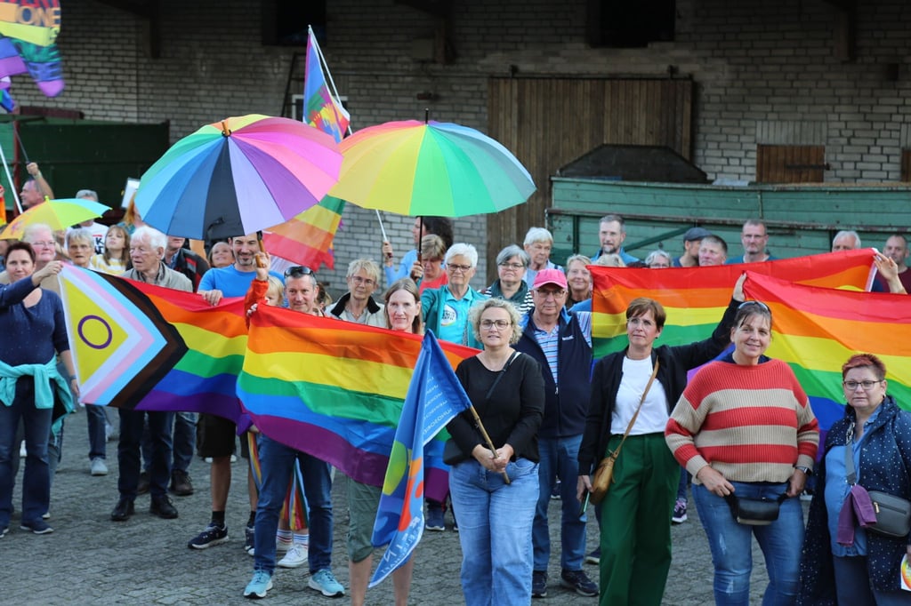 Menschen mit Regenbogenflaggen und -schirmen beteiligten sich an einer Kundgebung.