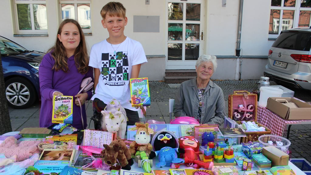 Caroline und Tim haben sich mit ihrem Stand voller Spiele, Kuscheltiere und Bücher einen guten Platz am Hagentorplatz ergattert. Oma Rita Falke hat die Geschäfte der beiden mit im Blick.