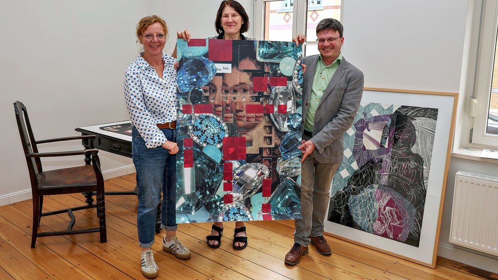 Katja Henze, Christina Simon und Maik Richter (v.l.n.r.) präsentieren die Collage „Sie hat“ von Anne Lange, eines von rund 50 Werken, die bei der Ausstellung „Dem eigenen Kompass folgen“ zu sehen sind.