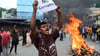 Ein Demonstrant in Nepal hält ein Blatt mit der Forderung nach einem Ende der Korruption hoch.