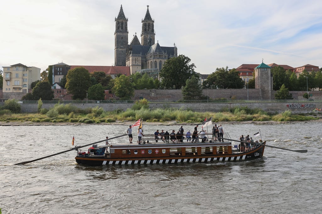 Die „Ulmer Schachtel“, ein Nachbau alter Donauschiffe, die für Transport und Handel genutzt wurden, passiert den Dom und Domfelsen auf der Elbe in Magdeburg.