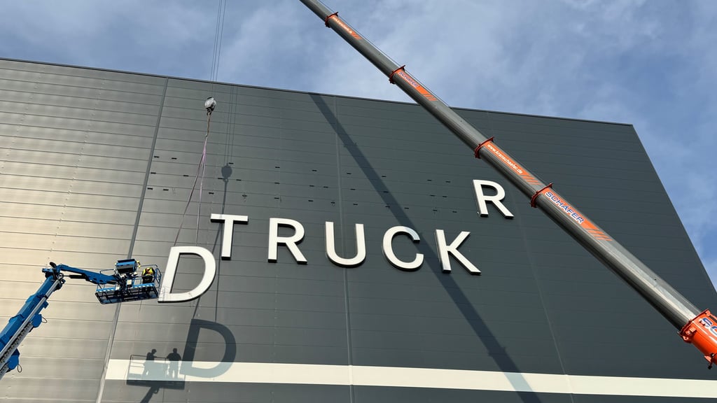 Der Firmenname wird am Hochregallager des neuen Global Parts Center von Daimler Truck in Halberstadt angebracht.