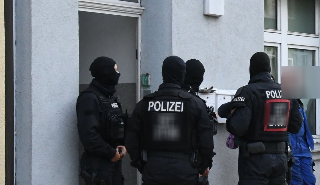 Vermummte Polizisten stehen am Mittwochmorgen vor einem Haus in der Sandstraße in Gardelegen.