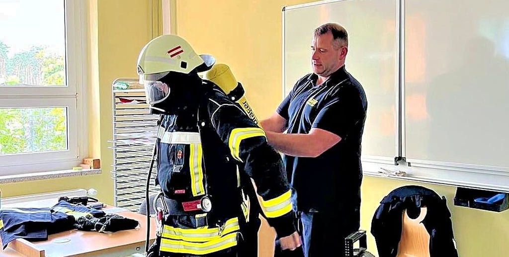 Manuel Schwendtke (rechts) und Robert Knoblauch führen die Einsatzkleidung für Feuerwehrleute in der Grundschule vor.