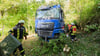 Einsatzkräfte der Feuerwehr stehen neben dem verunfallten Lkw an der Bundesstraße B3.