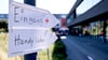 Richtungsschilder zur Ersten Hilfe und zum Handyladen hängen vor dem Technologiepark Adlershof.