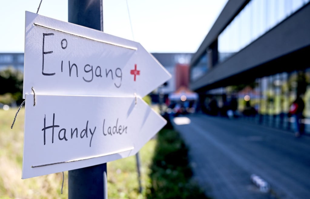 Richtungsschilder zur Ersten Hilfe und zum Handyladen hängen vor dem Technologiepark Adlershof.