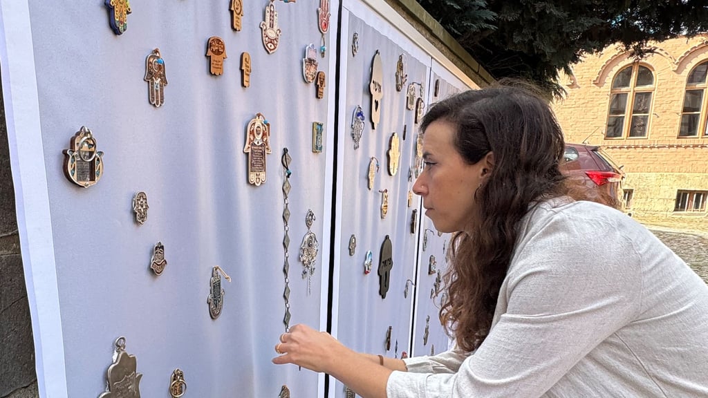 Hili Noy befestigt für die Ausstellung "Hamsa" zahkreiche dieser schutzbringenden Handsymbole an der Mauer im Hof der Klaus in Halberstadts Rosenwinkel 18.