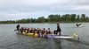 Zwanzig Paddler plus Schlag- und Steuermann sitzen beim Rennen in einem Drachenboot.  Auf dem Foto sind die  „H-Dragons“ aus Dessau-Roßlau zu sehen, die auf dem Mondsee gegen acht andere Teams antraten.