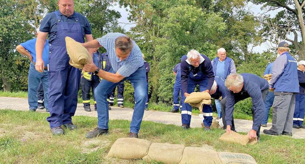 Mit Schwung muss der Sandsack an die liegenden gelegt werden. Dies zeigt Torsten Frischbier den Kameraden der Wasserwehr.