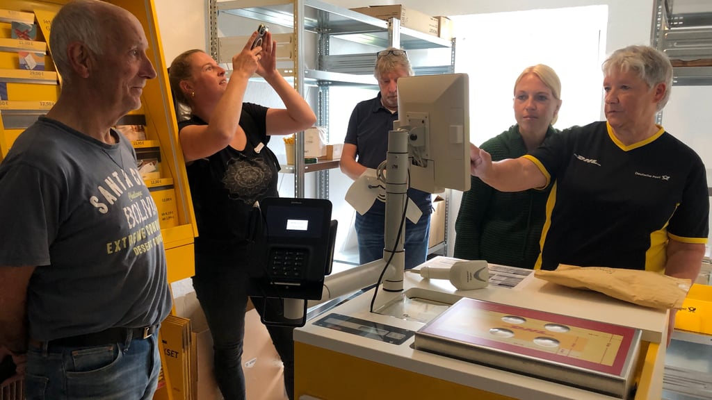 Gisbert Thater (l.) ist der erste Kunde in der neuen Partnerfiliale der Post in Bad Suderode. Kerstin Uhlemann (r.) und Heidi Schnoor (2. v. r.) nehmen den Brief, den er verschicken möchte, entgegen.
