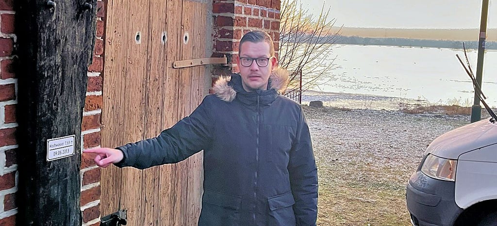 Ortsbürgermeister Alexander Wittwer bei Hochwasser an der Pegelmarke von 2013. Die obere Marke stammt aus dem Februar 1941. Damals waren wegen Eisgangs die Deiche gebrochen.