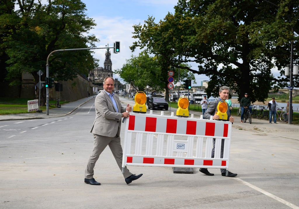 Dirk Hilbert (FDP, l), Oberbürgermeister der Stadt Dresden, und Stephan Kühn (Bündnis 90/Die Grünen), Baubürgermeister der Stadt Dresden, tragen den letzten Schrankenzaun vom Terrassenufer beiseite.