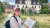 Kaya Schwab zeigt im Gelände des ehemaligen Rittergutes  Pauscha eine Mappe, die Ideen für die Entwicklung des Zukunftsdorfes enthält. 