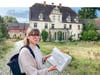 Kaya Schwab zeigt im Gelände des ehemaligen Rittergutes  Pauscha eine Mappe, die Ideen für die Entwicklung des Zukunftsdorfes enthält. 