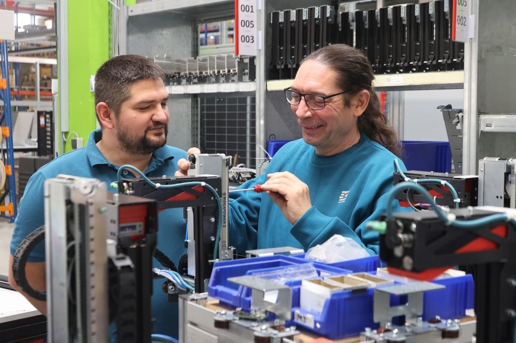 Konzentriert bei der Sache: Jens Bauling (rechts) und Gollmann-Produktionsleiter Alexander Ziegler, die für einen Automaten verwendeten Baugruppen an ein neues elektronisches Bauteil anzupassen.