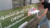 Ein Mitarbeiter des Orienta Supermarkts in Neu-Olvenstedt klebt ein Hakenkreuz ab. Es wurde mit blauer Grafitti-Farbe an das Werbebanner gesprüht.