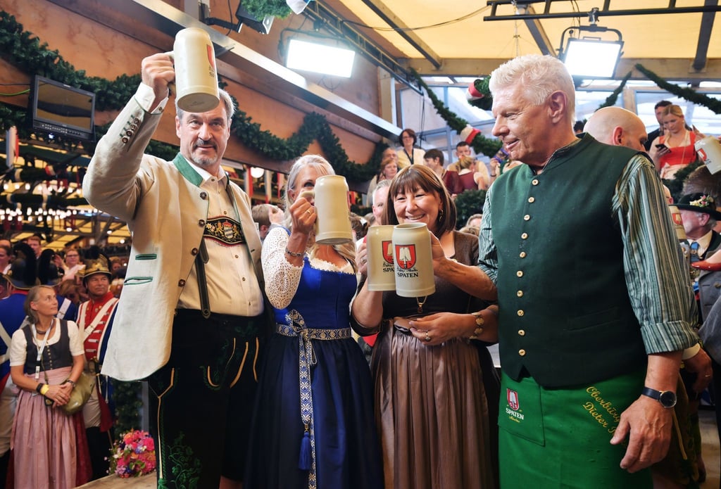 Bayerns Ministerpräsident Söder (l.) und Münchens OB Reiter (r.) stoßen mit ihren Ehefrauen auf eine friedliche Wiesn an.
