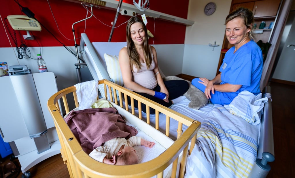 Im Klinikum Lüneburg werden Verena Ahrens und ihre wenige Tage alte Tochter von Hebamme Franziska Pfeil (r) betreut. Pfeil hat die erste Geburt im neu eröffneten hebammengeleiteten Kreißsaal im Klinikum Lüneburg betreut.