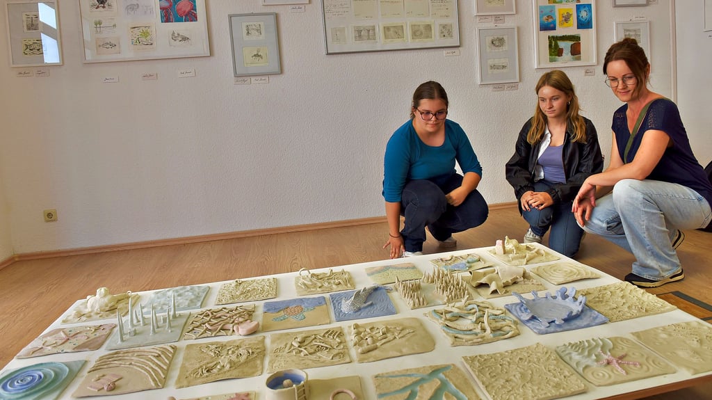 Anna und Maya (v. li.) haben an der Ausstellung „Wasser im Wandel“ mitgearbeitet und präsentieren sie den Besuchern, so wie Heidi aus Großörner, die sich die Keramiken zum Thema Wasser anschaut.