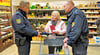 Die Polizeihauptmeister Torsten Gast (l.) und Jens Bertling weisen Kundin Kerstin Brandt aus Herrengosserstedt nicht nur darauf hin, ihre Handtasche lieber nah am Körper zu tragen, statt teils unbeaufsichtigt am Einkaufswagen zu platzieren, sondern geben ihr auch Infomaterial mit auf den Weg. 