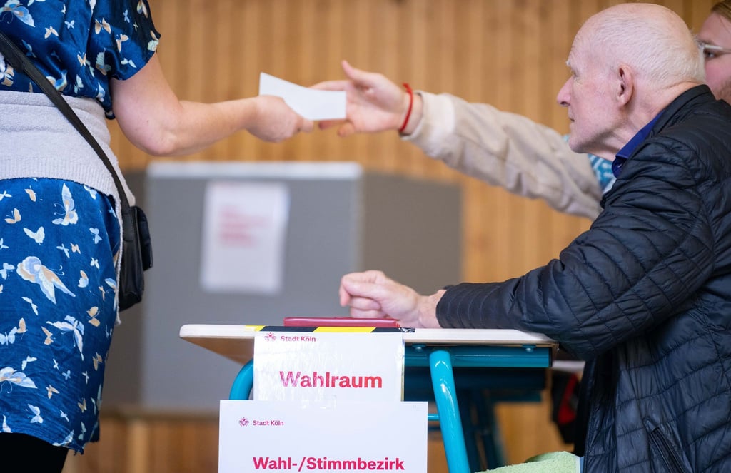 Eine Wahlhelferin gibt einen Stimmzettel aus. Landesweit fällt die Wahlbeteiligung unterschiedlich aus.