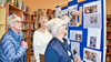 Bibliothekschefin Bärbel Dänecke zeigt den Besucherinnen Hanna Klietz und Giesela Cherek am Tag der offenen Tür die Ausstellung zum 33-jährigen Bestehen der Bibliothek auf der Wasserburg.  
