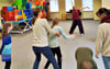 Melanie Stittrich (Hintergrund) gibt einen Tanzkurs  für Kinder von sechs bis zwölf Jahren mit Down-Syndrom.