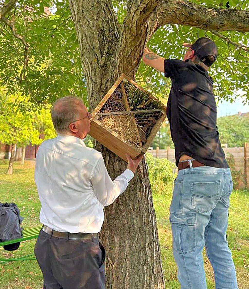 Regionalbischof Johann Schneider (l.) bringt das Insektenhotel mit an.