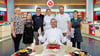 Matthias Engelmann (schwarzes Shirt) aus Köthen inmitten der „Küchenschlacht"-Gruppe: mit den Kandidaten Anja Rummel und Silvia Kurda, Moderatorin Viktoria Fuchs, Christian Kriegl und Alexandra Puric (v.li.) – und mit Thomas Martin, dem Juror vom Montag.