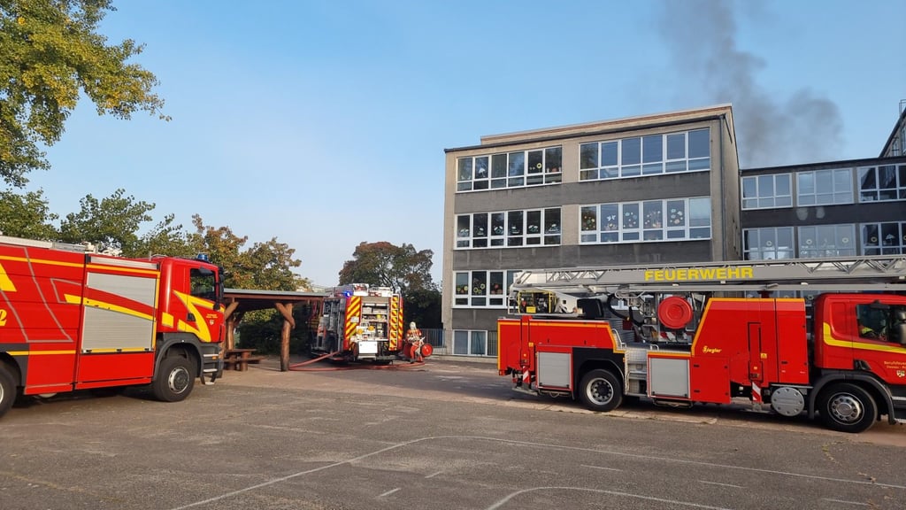 Die Feuerwehrleute vor der Pestalozzischule in Dessau. Qualm steigt auf.