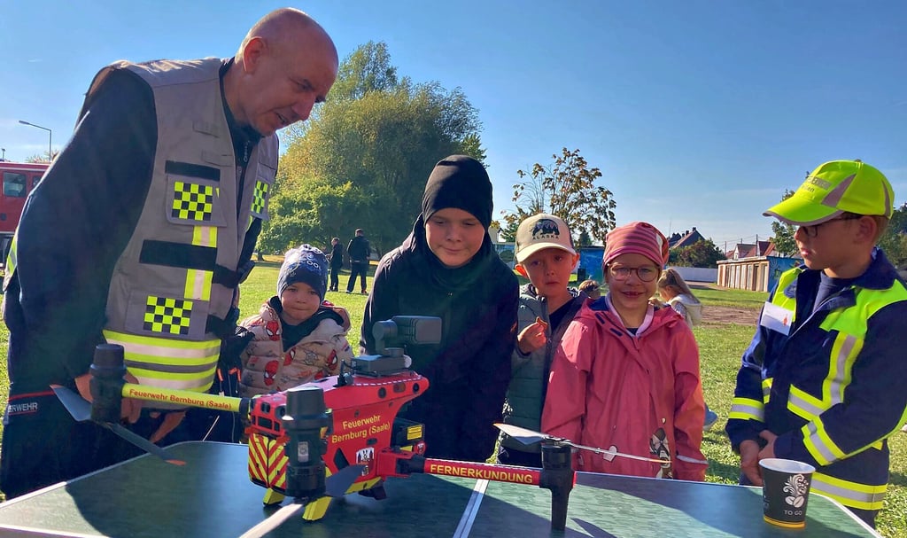 Drohnenpilot Steffen Streiber erklärt interessierten Kindern beim Tag der offenen Tür der Feuerwehr Peißen die Ausstattung der Drohne.