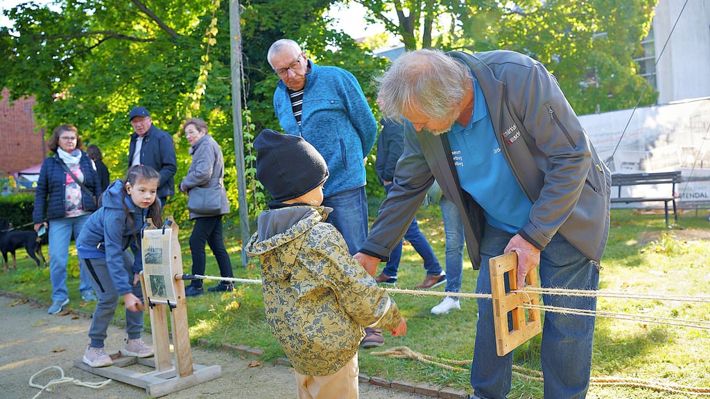 Detlef Preetz aus Osterburg (von rechts) erklärt Karl und seiner Cousine Merle beim Handwerkermarkt 2025 in Stendal ganz praktisch, wie Seile hergestellt werden.