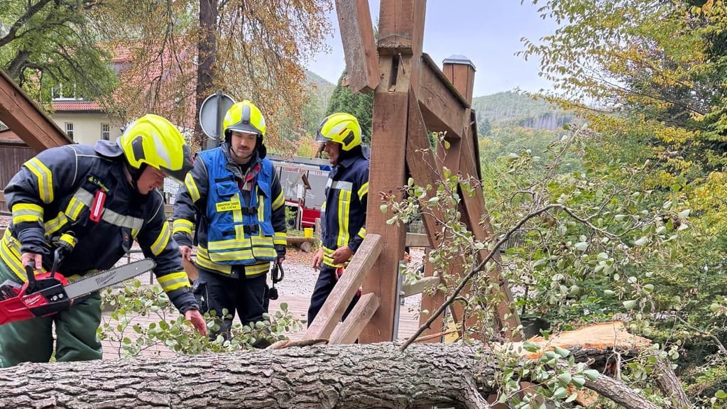 Feuerwehrmänner zersägen einen Baum, der auf die Blochhauer-Brücke in Ilsenburg gefallen ist und einen Teil der Konstruktion zerstört hat. Die Brücke am Ausgangspunkt vieler Wanderwege ist vorerst gesperrt.