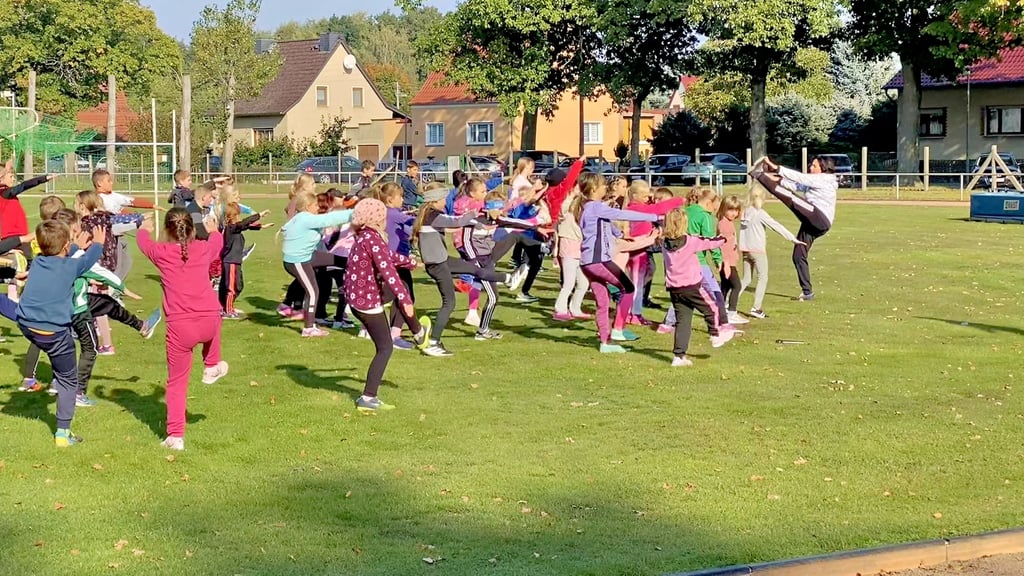 Sportlehrerin Jacqueline Meißner (re.) macht es vor, wie sich die Kleinen der Grundschule Annaburg vor ihrem Crosslauf erwärmen sollen.