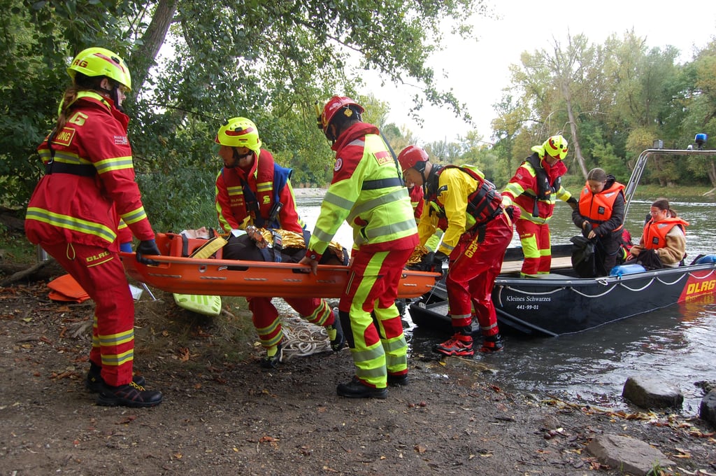 Einsatzkräfte der DLRG bringen Verletzte, die mit dem Boot geretten worden sind, an Land.