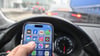 Nein, schlechte Idee: Wer im Auto ein Smartphone nutzen will, fährt besser rechts ran - und schaltet den Motor ab. Sonst könnte es teuer werden - gefährlich allemal.