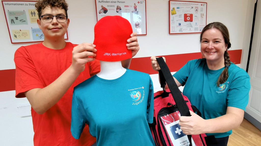 Letzte Vorbereitungen für die Ausstellung "100 Jahre Jugendrotkreuz" in Wernigerode: Sandra Giebel und Yannick Pust verpassen einer Puppe ein authentisches Outfit mit dem Logo und Equipment des Wernigeröder Jugendrotkreuzes. Sie wird die Schau in der Harzsparkasse dekorativ ergänzen.