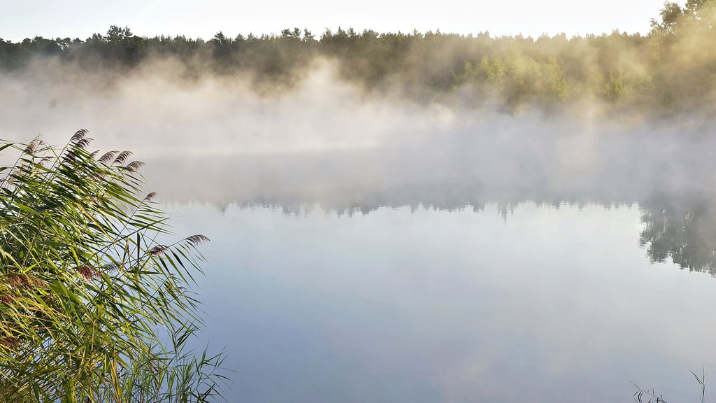 Ende September war das Wasser in den Badeseen noch 18 Grad warm. Am frühen Morgen, bei Temperaturen knapp über Null, dampft das Wasser im Licht der Morgensonne.