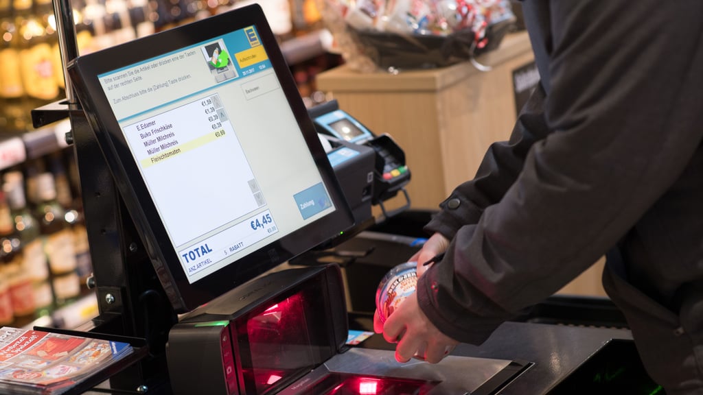 Jemand scannt seinen Einkauf bei Edeka an einer Selbstbedienungskasse.