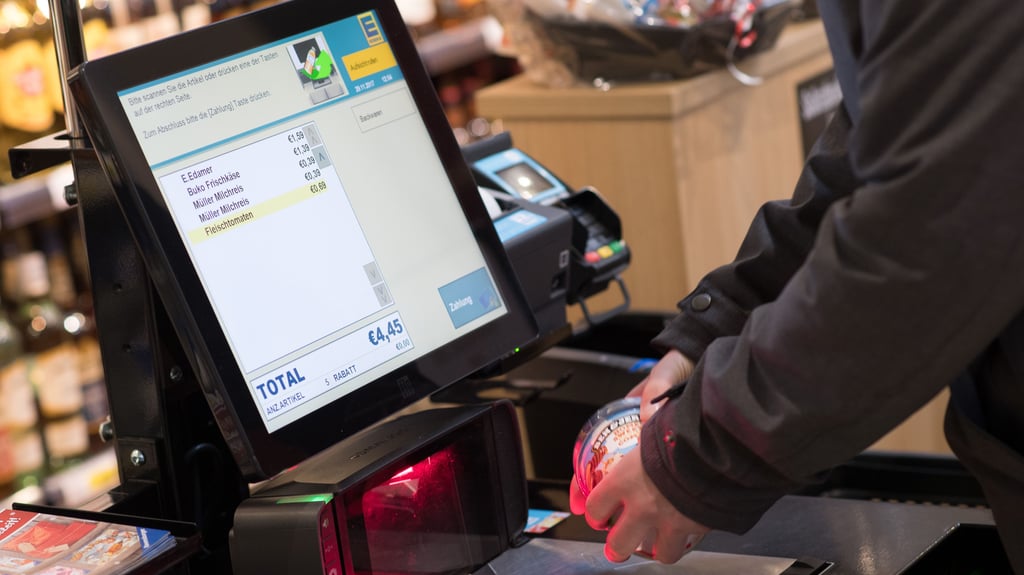 Jemand scannt seinen Einkauf bei Edeka an einer Selbstbedienungskasse.