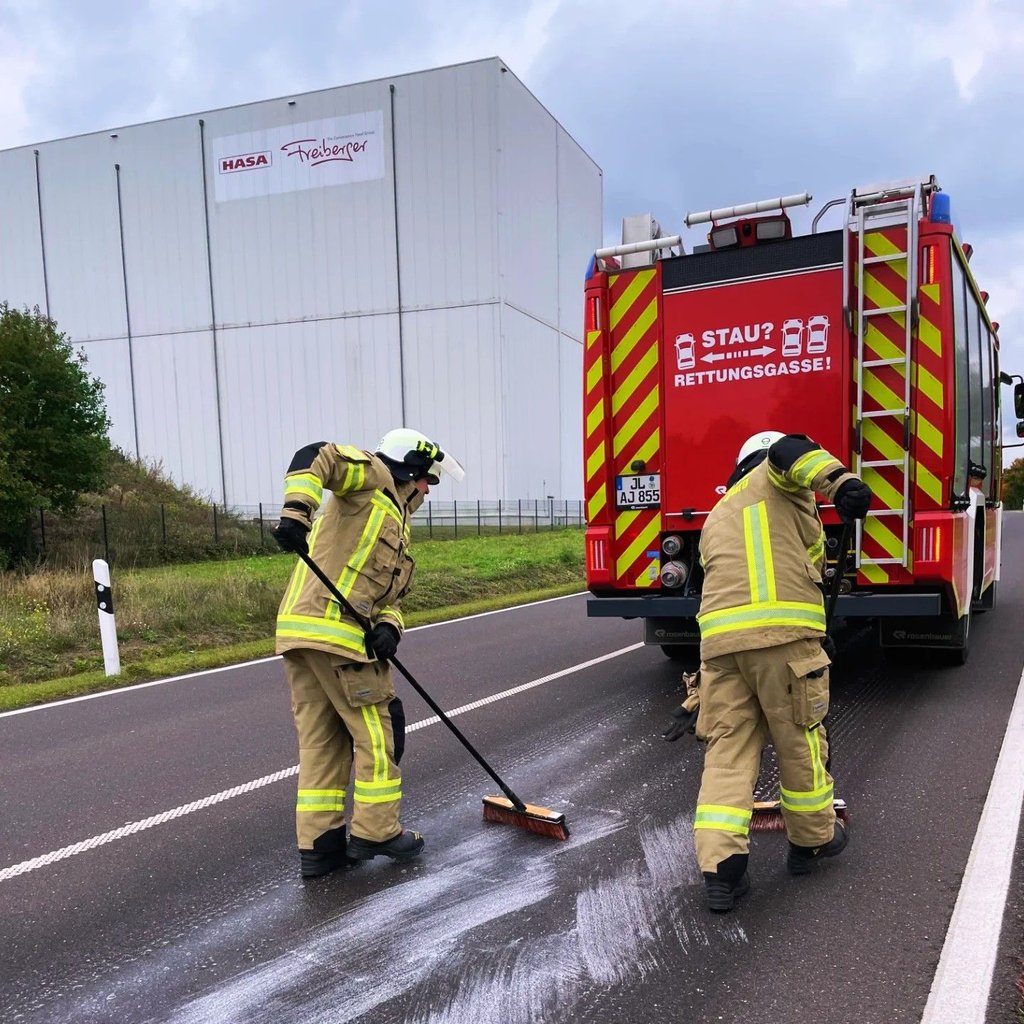 Die Einsatzkräfte der Feuerwehr Burg entfernen Rückstände einer Ölspur nahe des Gewerbegebietes.