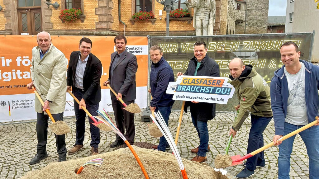 Bürgermeister Sven Hause (m.) und Theo Struhkamp (l.) nehmen den symbolischen Auftakt des geförderten Glasfaserausbaus in Calbe vor. Begleitet werden sie von Vertretern der Unternehmen.