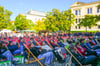 Dem Bühnenprogramm zur feierlichen Immatrikulation auf dem Uniplatz können Studierende im Liegestuhl zusehen.