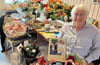 Edith Braun in einem Raum voll Blumen und Glückwünsche. Zu den Überraschungen gehörte unter anderem ein Buch des Lüderitzer Männergesangsvereins, für den sich die Ortsbürgermeisterin von Lüderitz, wie für alle Vereine im Ort, stark macht.