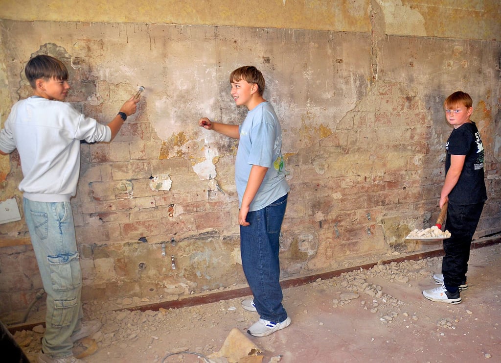 Elias (von links), Lorenz und Nathan beim Putzabklopfen im künftigen Gemeinschaftsraum.