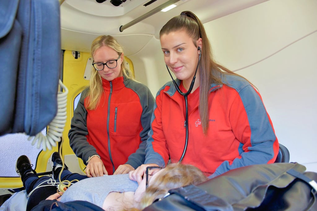 Auszubildende Amina Jouhri (re.) und Justine Henschel checken den Zustand einer jungen Frau (Szene nachgestellt).